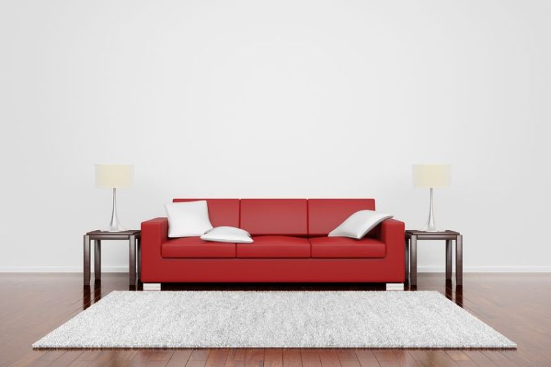 12065689 - red couch on wooden floor with white cushions carpet and lamps