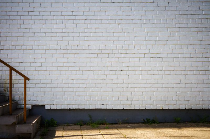 34488435 - old brick wall painted white and a side walk