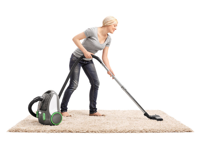 38347293 - full length portrait of a woman vacuuming a beige colored carpet with a vacuum cleaner isolated on white background